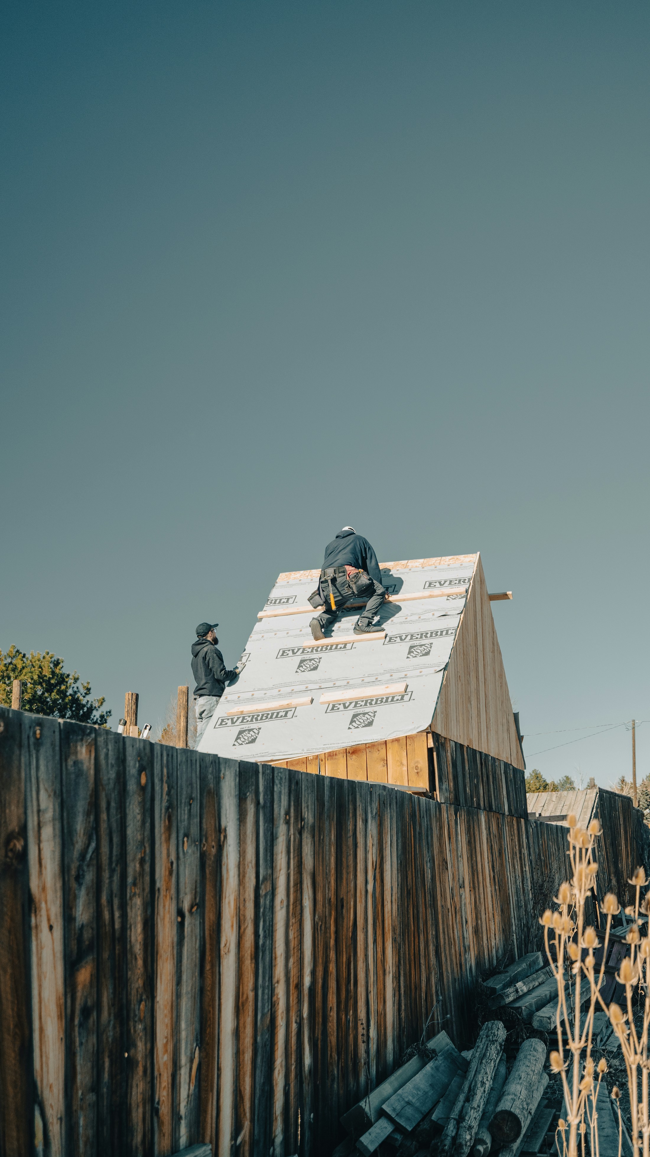 Roofing crew framing a residential roof under a clear sky